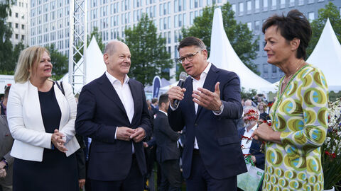 Von links nach rechts: Bundesinnenministerin Nancy Faeser, Bundeskanzler Olaf Scholz, Ministerpräsident Boris Rhein – mit Mikrofon in seiner rechten Hand – und Staatsministerin Lucia Puttrich