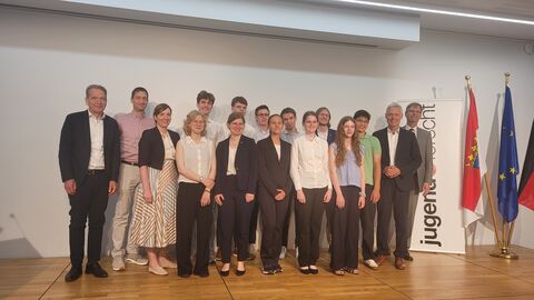 Mehrere Schüler und Staatssekretär Lösel stehen nebeneinander auf einer Bühne.