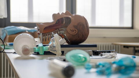 Kopf einer Lernpuppe und Beatmungsgerät auf einem Tisch